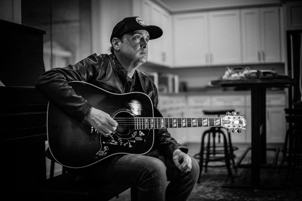 Bo Adams with acoustic guitar at home, black and white