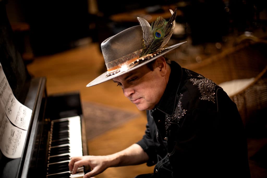 Bo Adams at the piano in a feathered hat